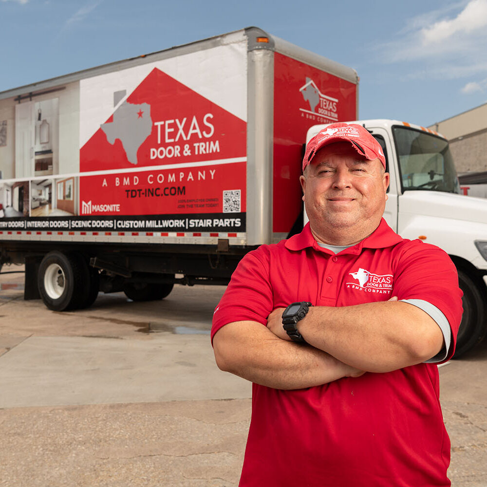 Worker standing in front of a company truck with graphics on the truck box side.